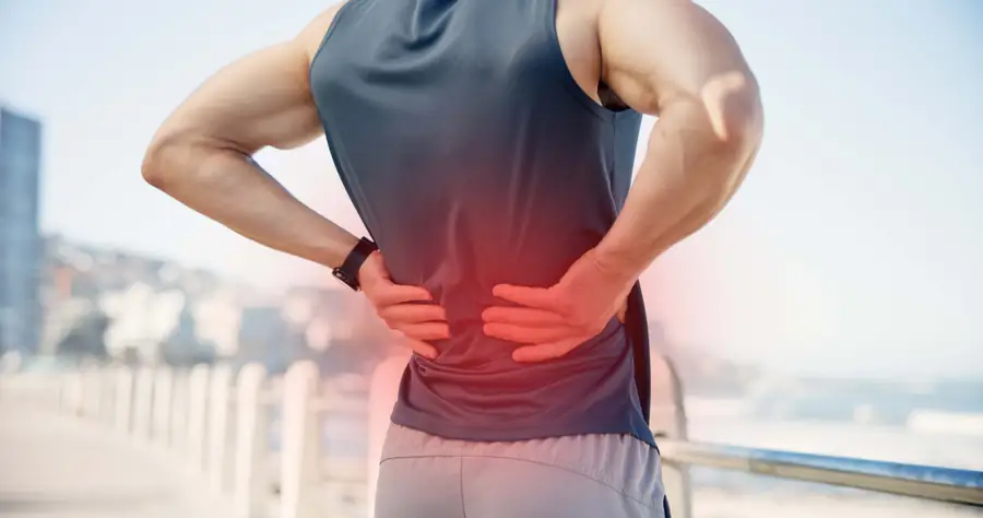 Athletic man holding his lower back with the painful area highlighted in red
