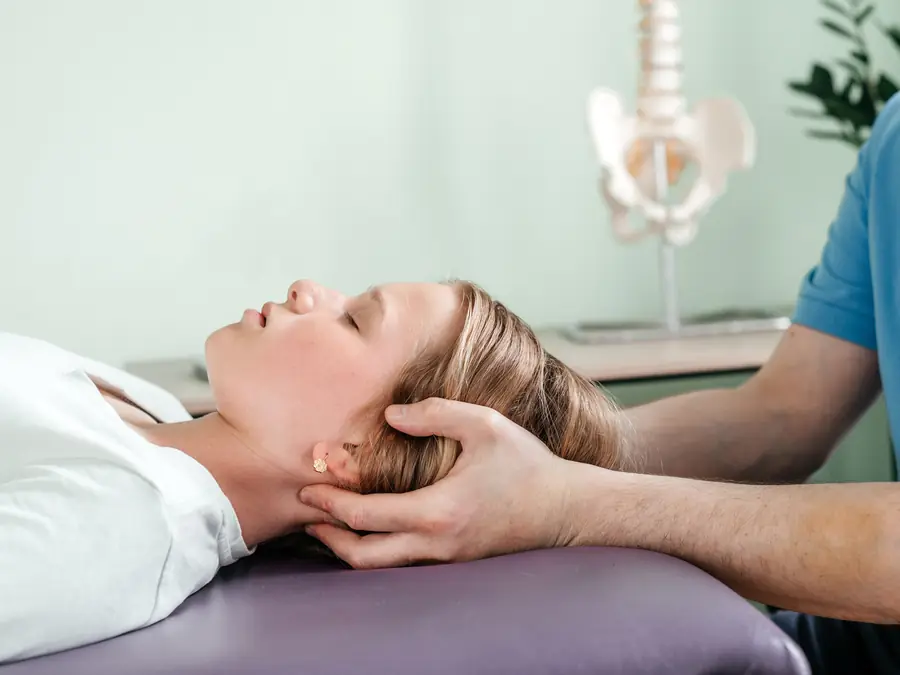 Chiropractor gently supporting a patient's head and neck on a treatment table