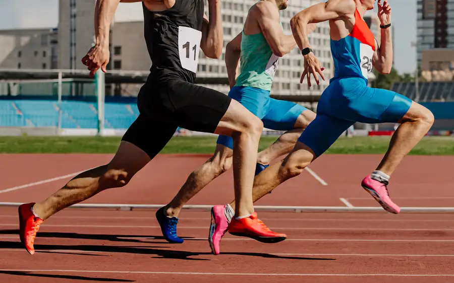 Three sprinters driving off the line on a red running track