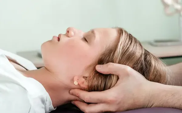 Woman resting on a treatment table while a chiropractor gently supports her head and neck